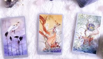 A mystical arrangement of tarot cards with flowers and crystals on a white textured surface, perfect for divination themes.